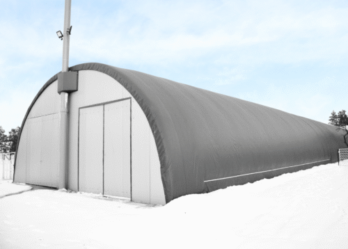 Namiotowa hala chłodnicza z ciemnym poszyciem, dostosowana do pracy w warunkach zimowych. Konstrukcja wyposażona w duże dwuskrzydłowe drzwi ułatwiające transport i składowanie towarów, zapewniająca stabilne warunki temperaturowe oraz ochronę produktów wrażliwych na mróz i wilgoć.