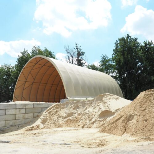 Hala namiotowa z jasnym poszyciem zlokalizowana przy utwardzonym placu, obok którego składowane są duże hałdy piasku. Konstrukcja hali opiera się na stalowym stelażu i betonowych murkach oporowych.