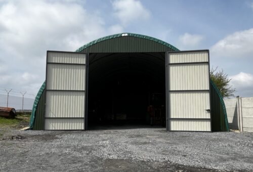 Wiata w kształcie hali łukowej z otwartymi na oścież drzwiami wejściowymi.