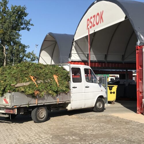 Biały wóz dostawczy z materiałami odpadowymi wjeżdża do hali łukowej punku selektywnej zbiórki odpadów.