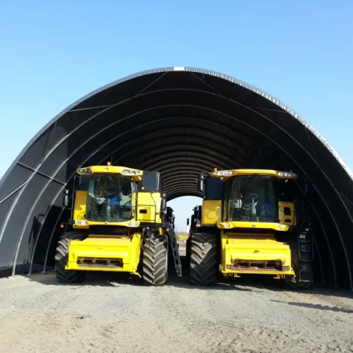 Hala namiotowa 12x30 metrów o stalowej konstrukcji i czarnym poszyciu, przeznaczona do przechowywania maszyn rolniczych. Wewnątrz widoczne są dwa żółte kombajny, które bez problemu mieszczą się w jej wysokim wnętrzu.