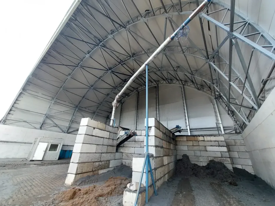 Wnętrze hali szkieletowej z wybudowanymi ściankami działowymi. Pod sklepieniem widoczny jest szkielet hali, pokryty białą plandeką.