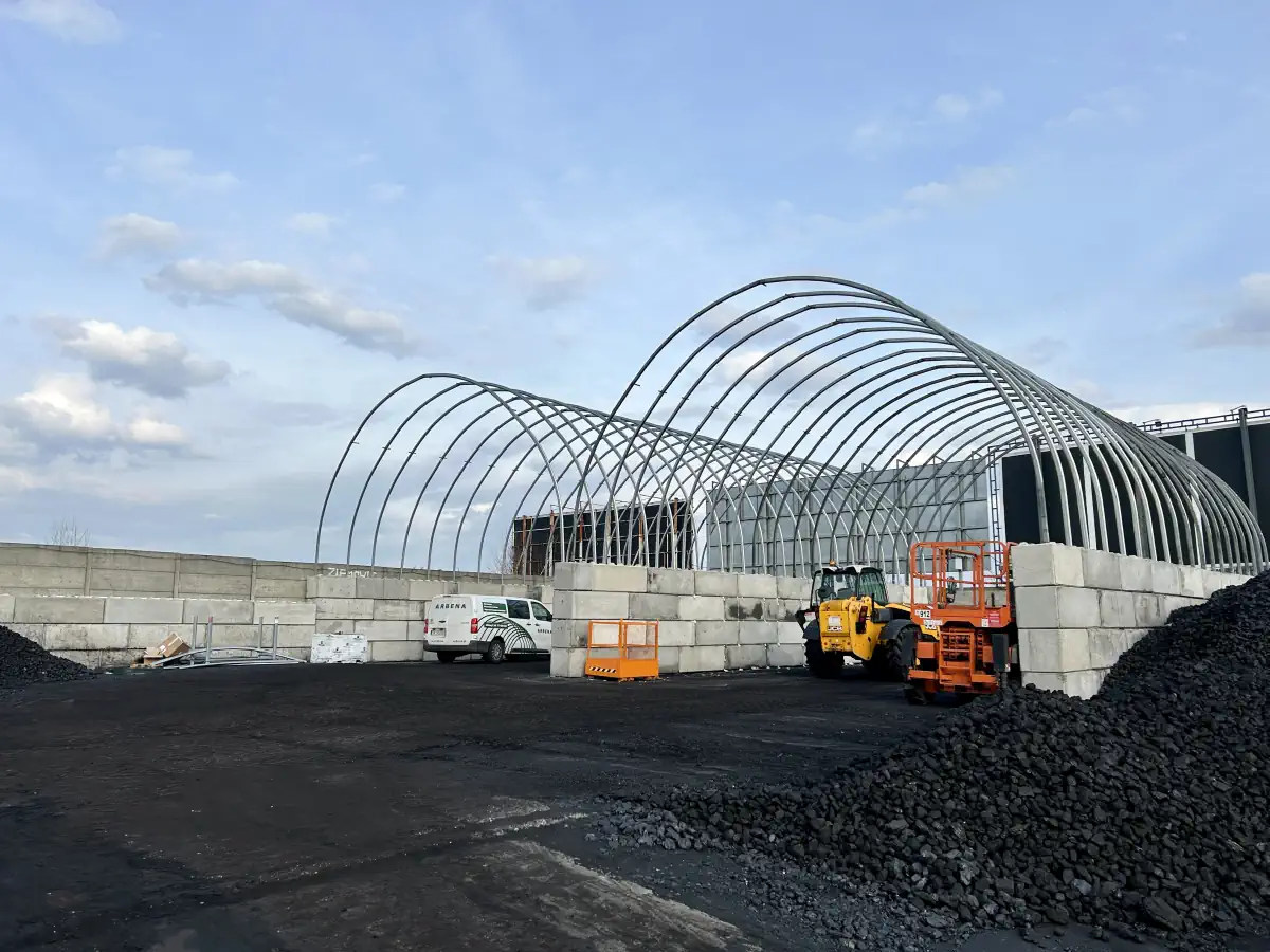 Widoczny jest kompletny szkielet hali namiotowej - fundament z bloczków betonowych w połączeniu ze stelażem zadaszenia hali.