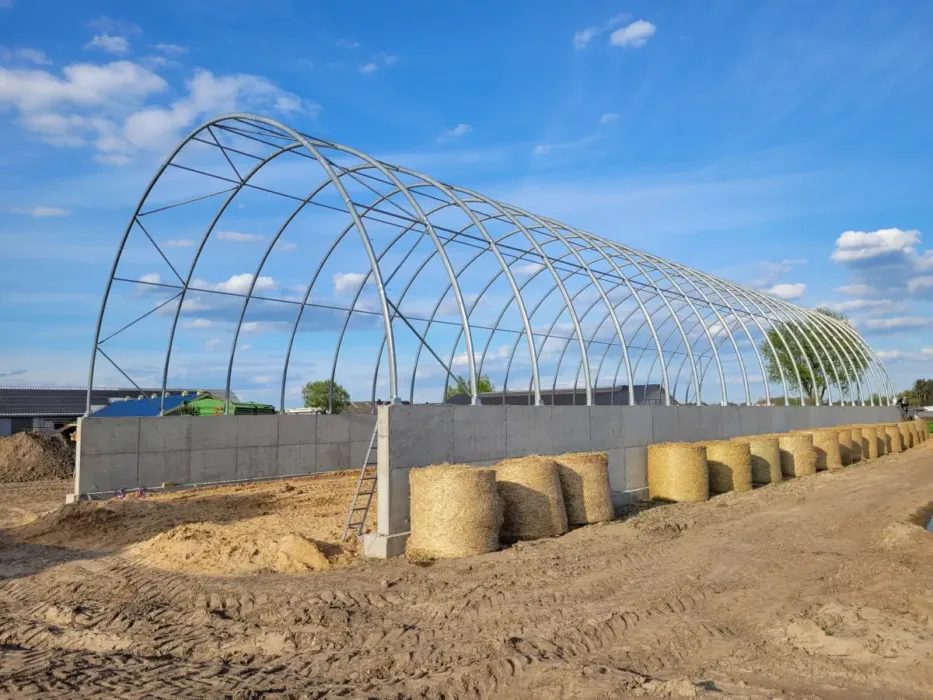 Stelaż metalowej hali łukowej postawionej na bloczkach betonowych.