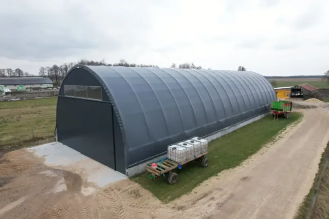 Czarne poszycie hali namiotowej. Ujęcie pokazuje hale tunelową, która może zostać zaadaptowana do różnych celów gospodarczych i przemysłowych.