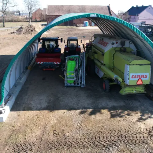 Namiot garażowy 10x15x1,5 m z ciągnikami i prasą rolniczą wewnątrz. Solidna hala namiotowa chroniąca wartościowy sprzęt gospodarstwa.