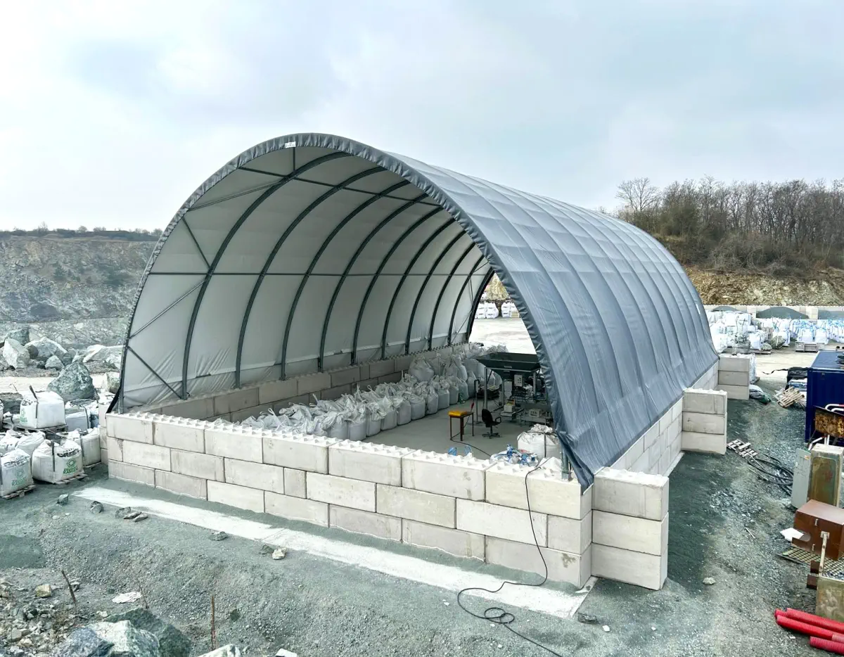 Wiata z membrany oparta na murkach z bloków betonowych tworzy osłonięte stanowisko pracy w kamieniołomie. Wewnątrz znajdują się big bagi i stanowisko do ważenia lub konfekcjonowania.