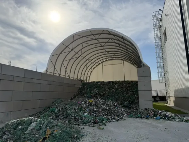Hala namiotowa posadowiona na betonowych bloczkach z odpadami pod sklepieniem oraz przed halą.