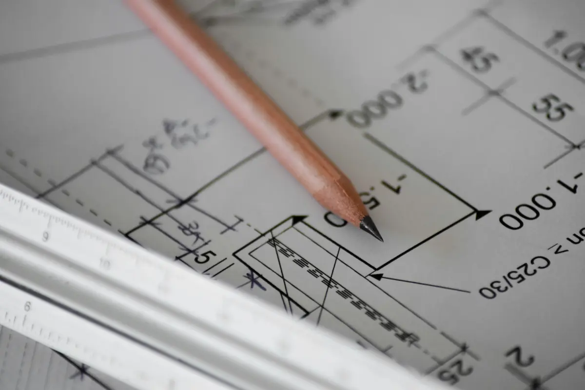 Plan architektoniczny narysowany na papierze. Na planie leży ołówek.