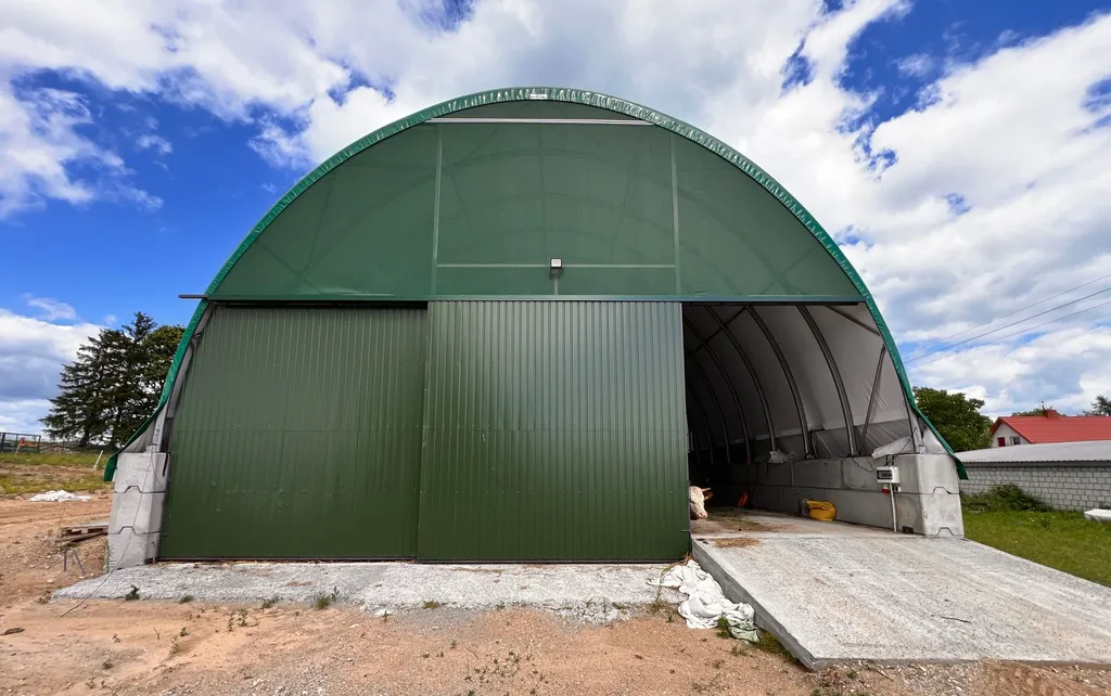 Hala łukowa pokryta zieloną plandeką, widok z zewnątrz