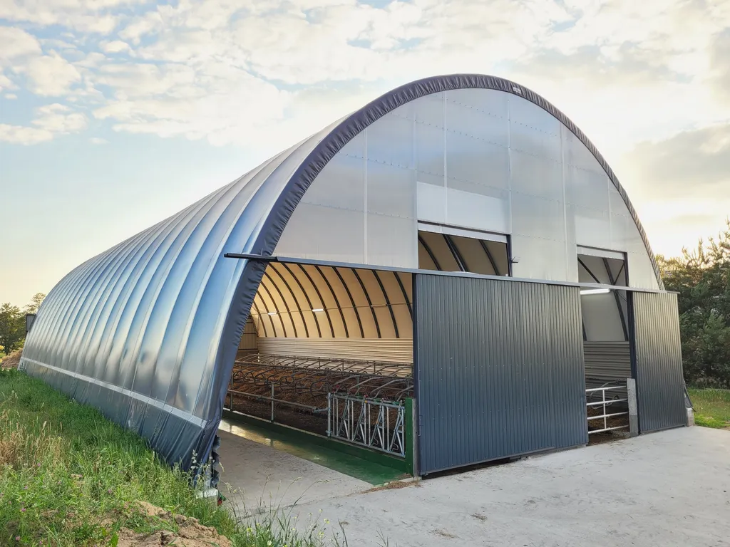 Jasna hala tunelowa dla bydła z otwartą bramą