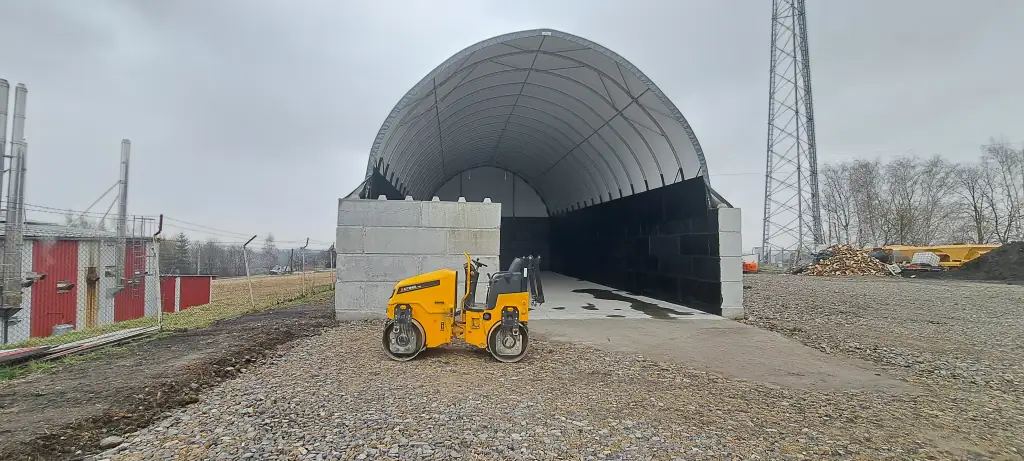 Hala łukowa na działce przemysłowej z utwardzonym dojazdem i ścianami bocznymi z bloków betonowych