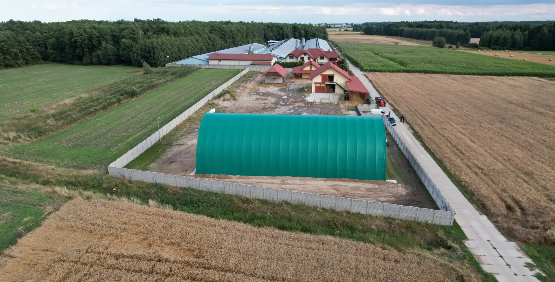 Hala łukowa postawiona na działce rolnej w otoczeniu pól i zabudowy gospodarczej